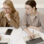two women with laptops